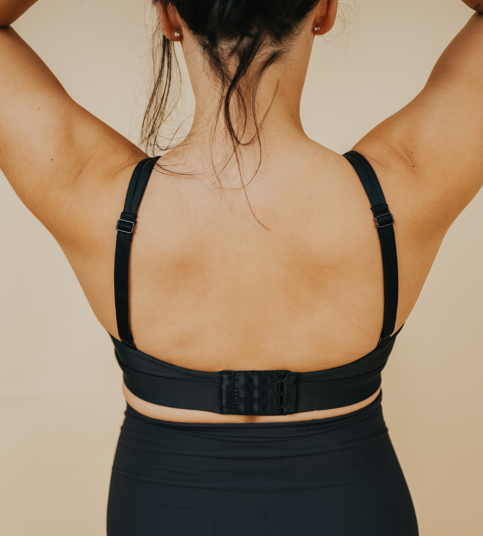 Back view of active mum wearing black nursing sports bra with crossover straps