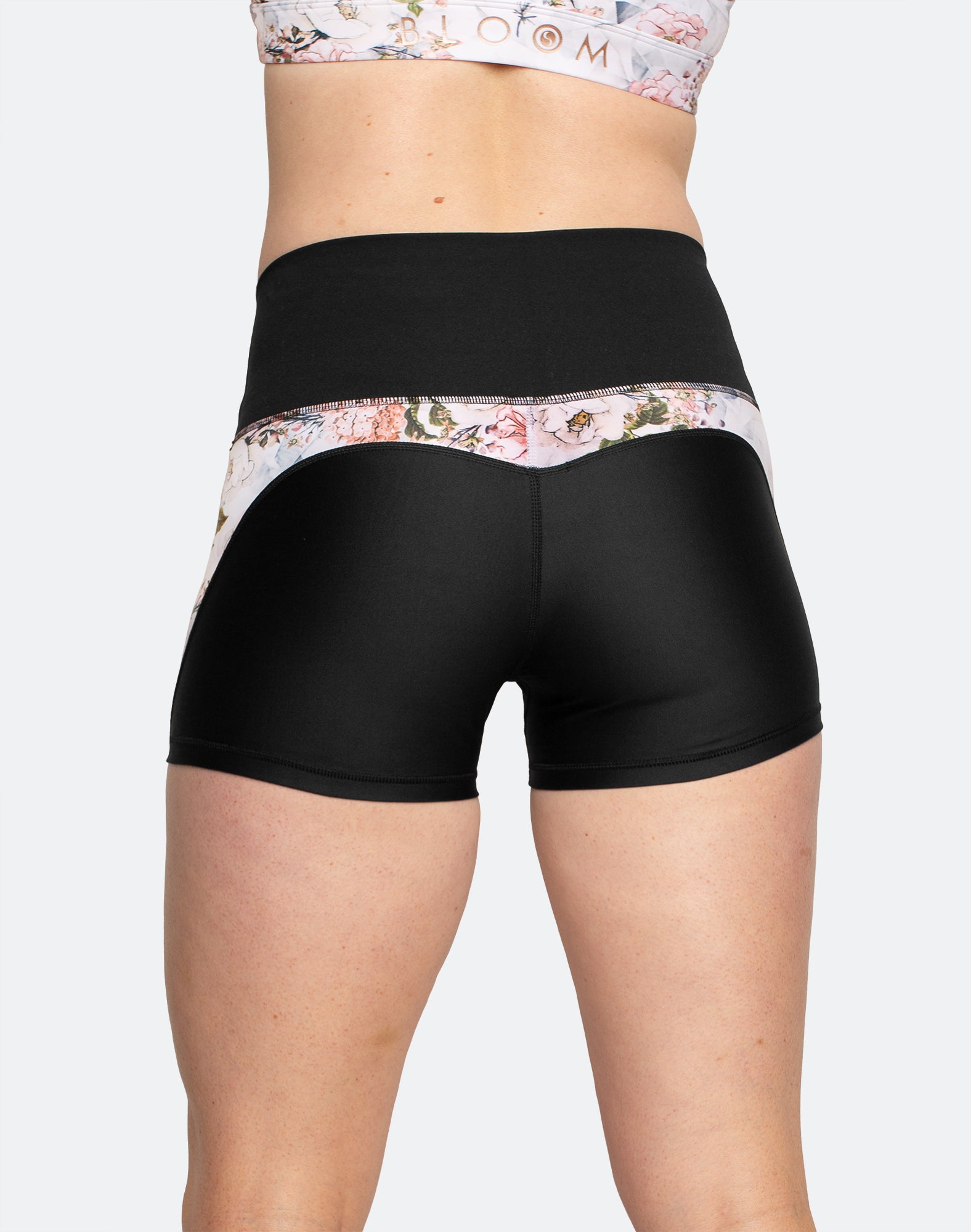 back view of black 3 inch maternity shorts with white floral detailing