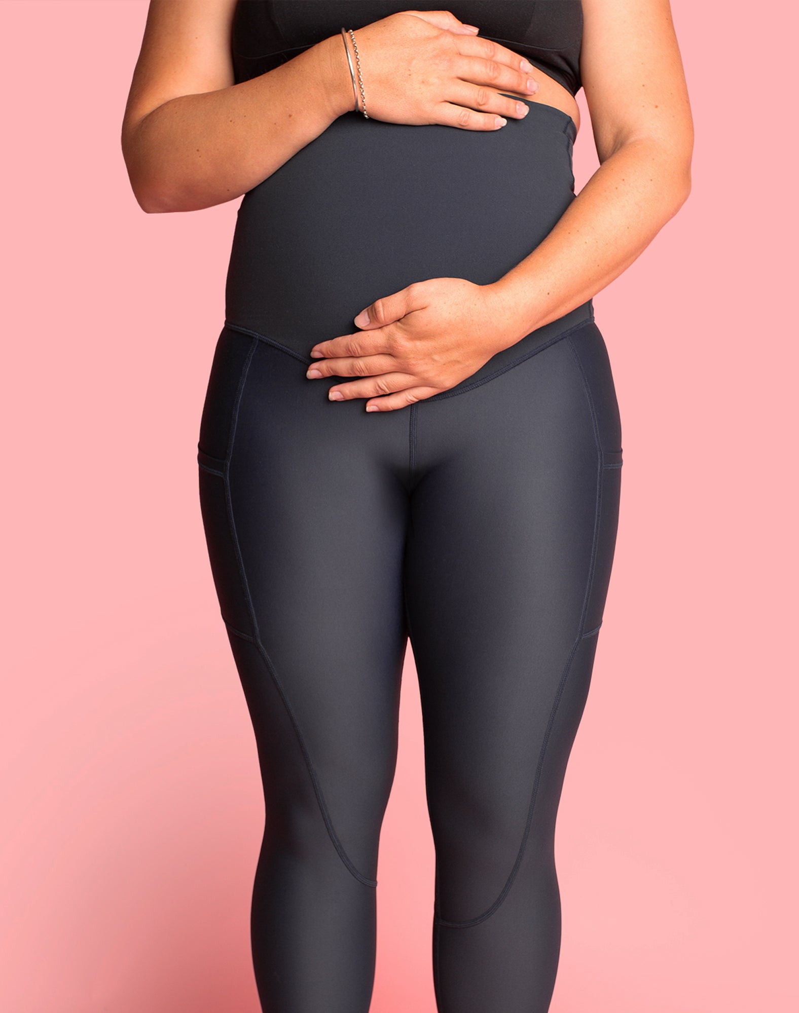 Pregnant mother holding her bump wearing dark blue pregnancy leggings