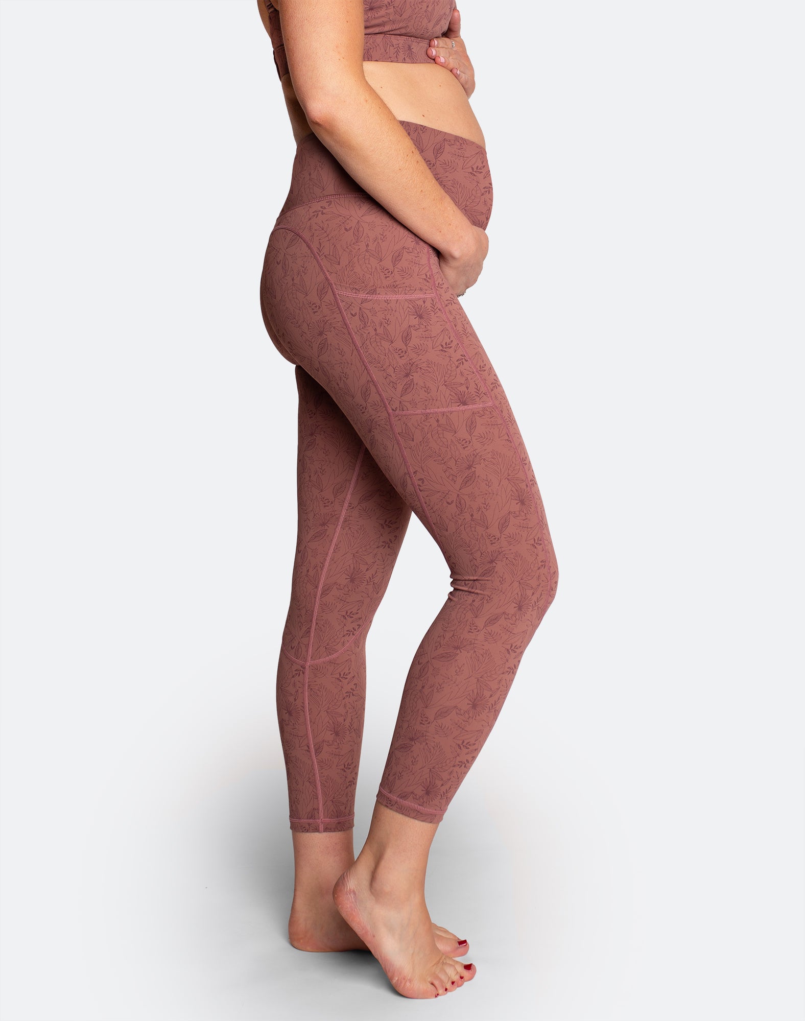 Side view of pregnant mum holding her bump wearing high waisted leggings