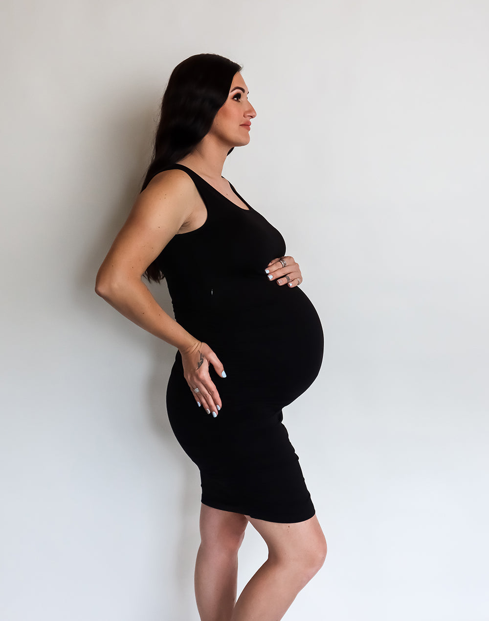 Side view of pregnant mother wearing black maternity tank dress